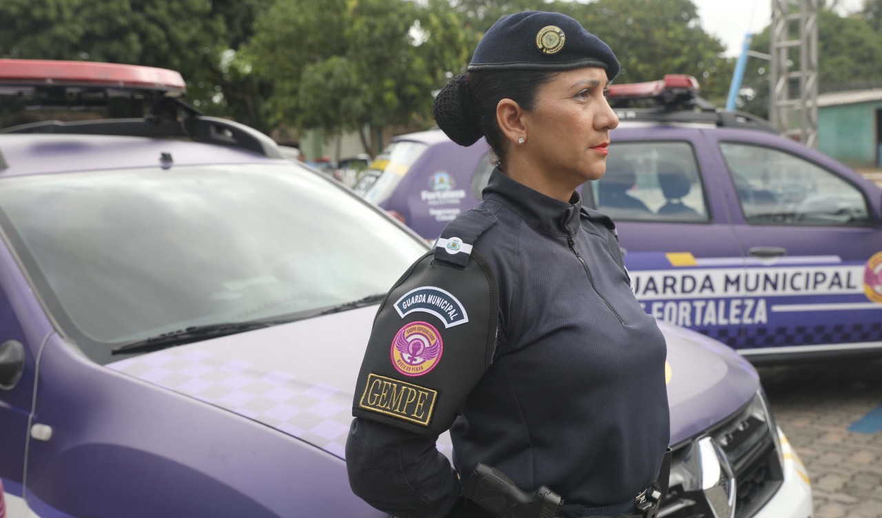 guarda municipal na frente de um carro da corporação